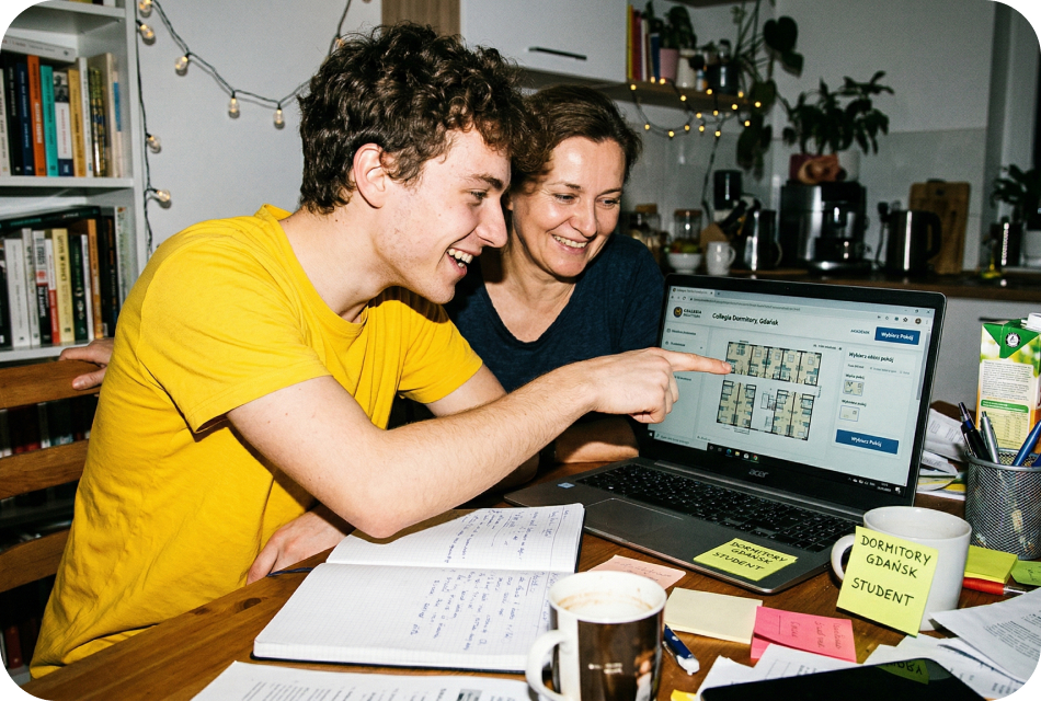 Two students at a kitchen table browsing the Student Depot booking site on a laptop